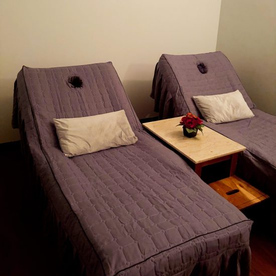 Two Cozy Massage Beds with Pillows and Side Table in Spa